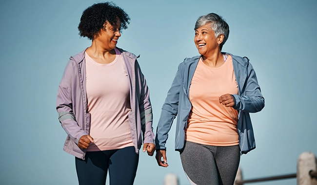 two middle age women walking outside smiling